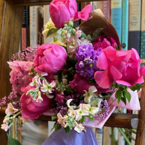 Wrapped bouquet of peonies, lilacs, and stock flowers