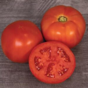 Three red ripe beefsteak tomatoes, one is sliced in half